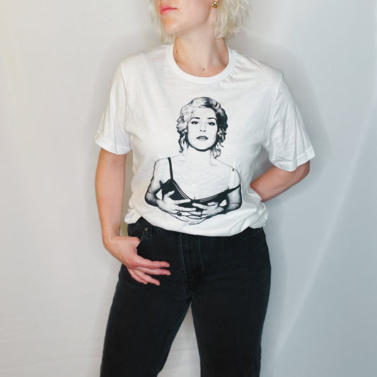 Blonde woman wears a white t-shirt and black jeans; the t-shirt is of a black and white photo of the artists VISSIA