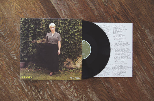 VISSIA Place Holder black LP; the cover shows a short haired blonde woman in long black skirt and grey button-up shirt posing against a wall of green vines
