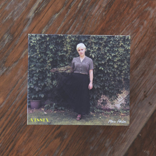 VISSIA Place Holder CD; the cover shows a short haired blonde woman in long black skirt and grey button-up shirt posing against a wall of green vines